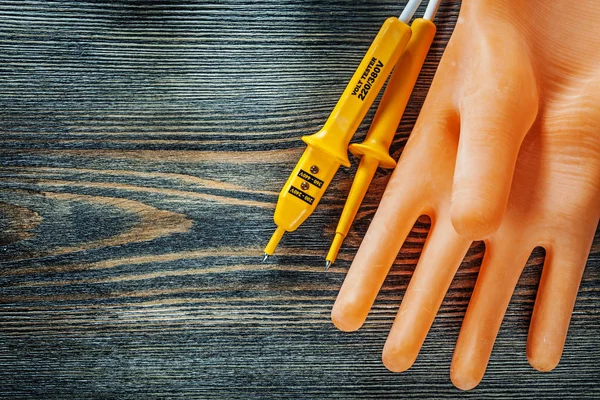 Electricians gloves electric tester on wooden board