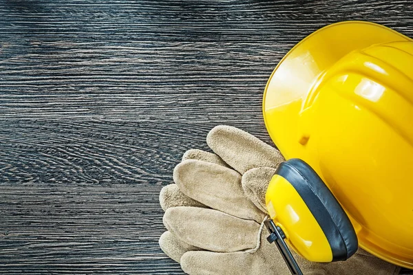 Helm oorkappen lederen beschermende handschoenen op houten bord — Stockfoto