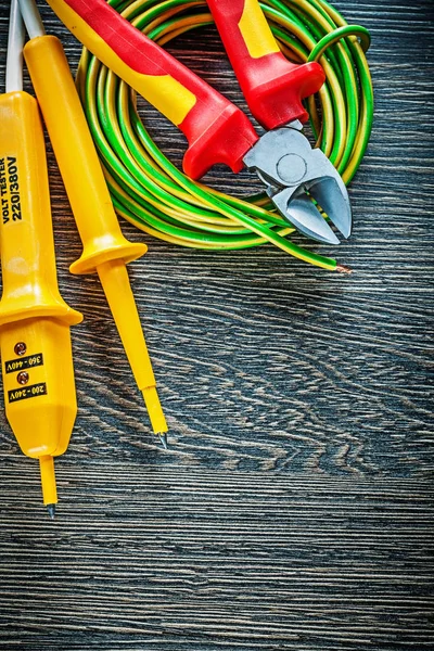 Electric tester cutting pliers rolled cable on wood board — Stock Photo, Image