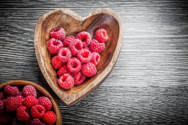 Ahşap tahta üzerinde olgunlaşmış ahududu ile ahşap kase