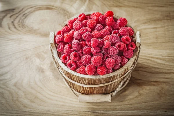 Bucket with raspberries on wooden board — Stock Photo, Image