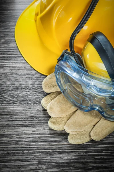 Safety gloves glasses earmuffs building helmet on wooden board — Stock Photo, Image