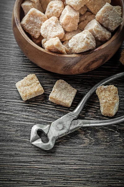 Cane sugar pliers round bowl on vintage wood board — Stock Photo, Image