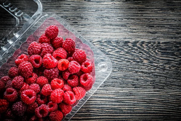 Raspberry in container on wooden board — Stock Photo, Image
