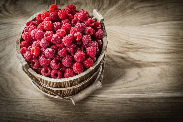 Red raspberries in bucket on wooden board top view — Stock Photo, Image