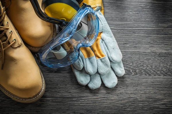 Sicherheitshandschuhe stiefel brille ohrenschützer auf holzbrett — Stockfoto