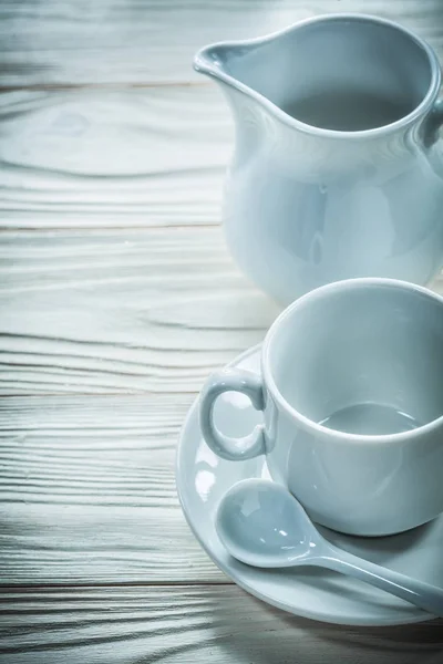 Platillo taza de cerámica cucharadita de leche jarra en tablero de madera — Foto de Stock