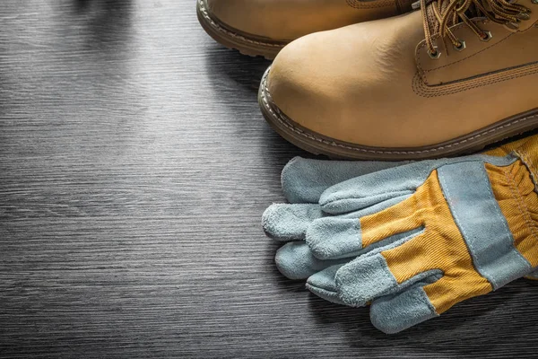 Guantes protectores botas de trabajo sobre tabla de madera — Foto de Stock