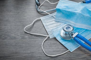 Tek kullanımlık gribi yüz maskeleri stetoskop ahşap tahta üzerinde