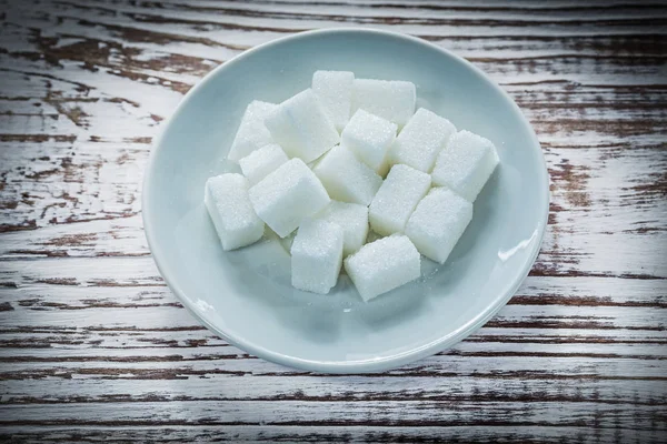 Teller mit Zuckerwürfeln auf Holzbrett — Stockfoto