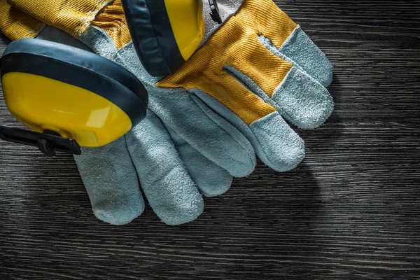 Oorkappen paar beschermende handschoenen op houten bord — Stockfoto