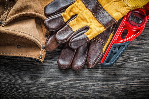 Construction level pair of safety gloves leather tool belt on wo — Stock Photo, Image