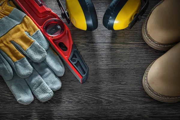 Earmuffs safety gloves boots construction level on wooden board — Stock Photo, Image