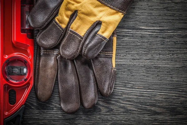 Construction level working gloves on wooden board — Stock Photo, Image