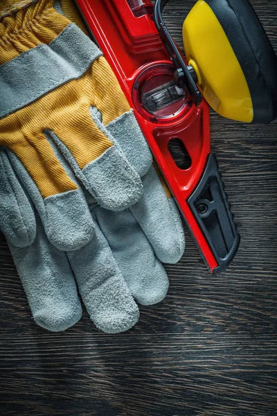 Earmuffs safety gloves construction level on wooden board — Stock Photo, Image