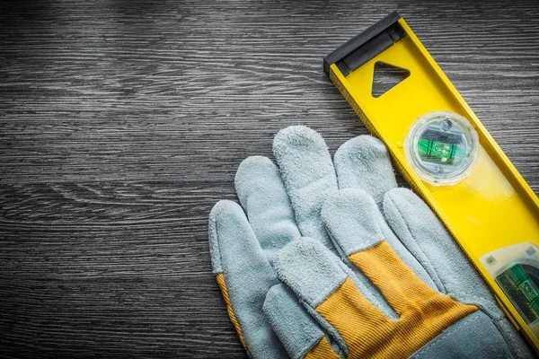 Yellow construction level protective gloves on wooden board — Stock Photo, Image