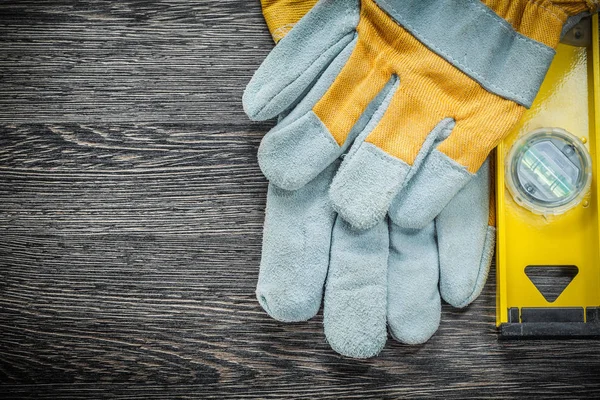 Yellow construction level safety gloves on wooden board — Stock Photo, Image