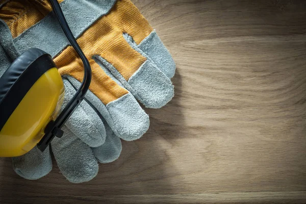 Ear muffs protective gloves on wooden board — Stock Photo, Image