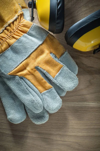 Ear muffs safety gloves on wooden board — Stock Photo, Image