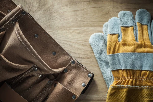 Leather building belt pair of protective gloves on wooden board