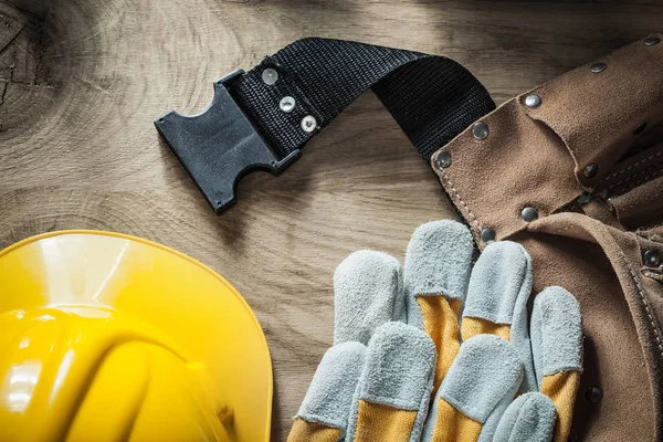 Leather construction belt safety gloves hard hat on wooden board