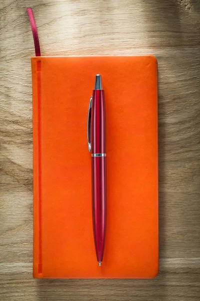 Stylo carnet orange sur planche en bois — Photo