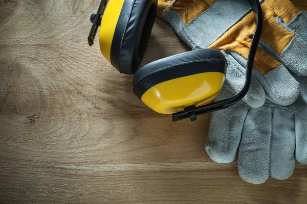 Noise reduction earmuffs safety gloves on wooden board — Stock Photo, Image