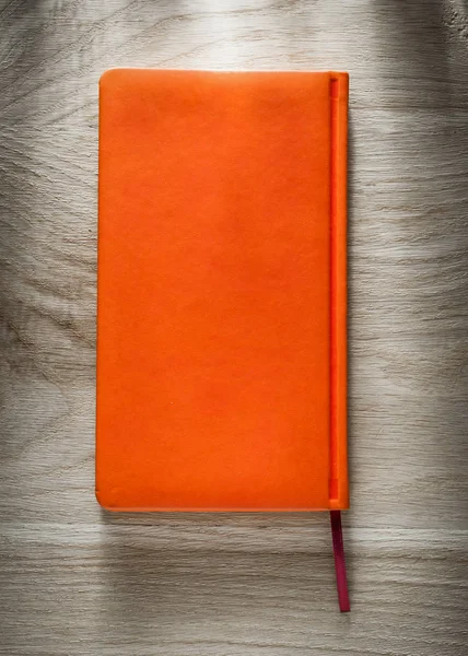 Cuaderno naranja sobre tabla de madera — Foto de Stock