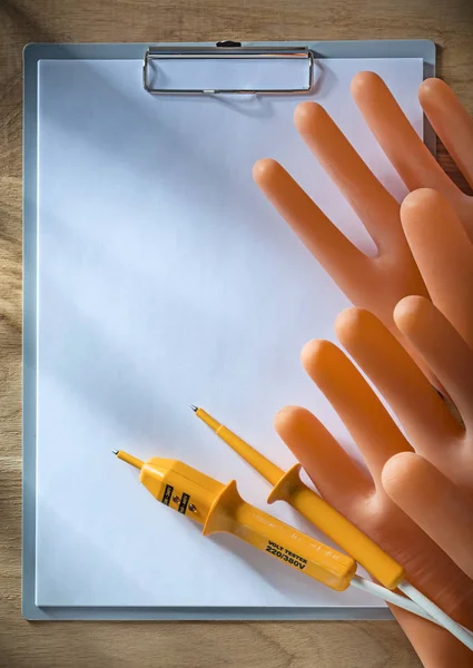 Clipboard paper electric tester insulating gloves on wooden boar — Stock Photo, Image