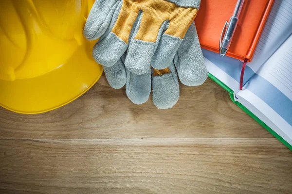 Protective gloves notepads pen hard hat on wooden board — Stock Photo, Image