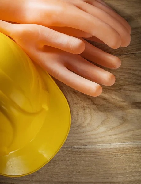 Guantes aislantes sombrero duro en tablero de madera —  Fotos de Stock