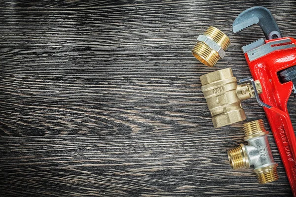 Plumbing monkey wrench pipe connectors on vintage wooden board — Stock Photo, Image