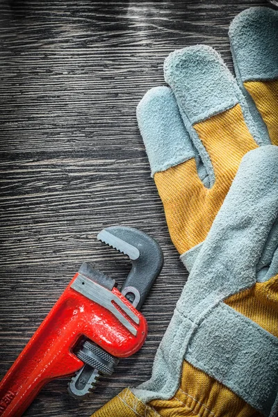 Plumbing adjustable wrench protective gloves on wooden board — Stock Photo, Image