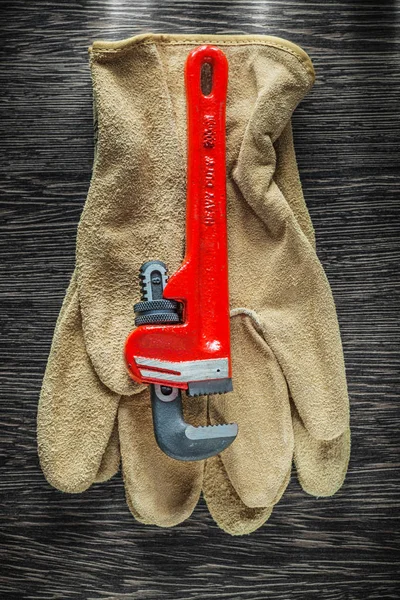 Pair of safety gloves plumbing pipe wrench on wooden board — Stock Photo, Image