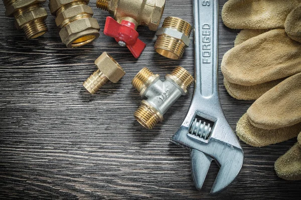 Adjustable wrench water valve pipe fittings safety gloves on woo — Stock Photo, Image