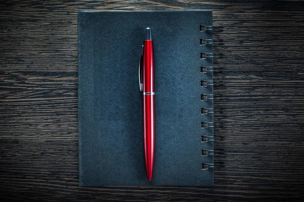 Black notepad pen on vintage wooden board directly above