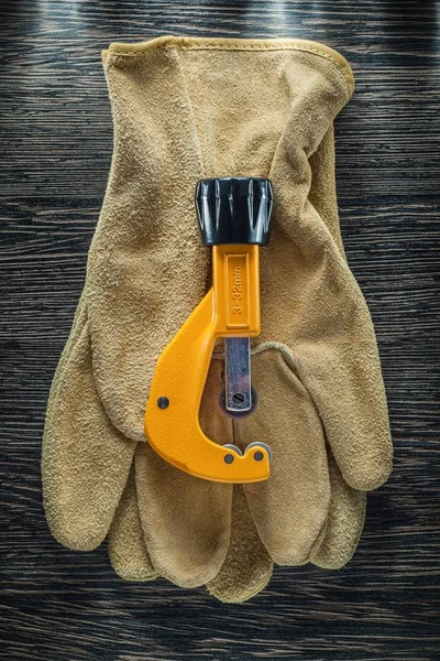 Tubo de fontanería cortador guantes de seguridad de cuero en tablero de madera —  Fotos de Stock