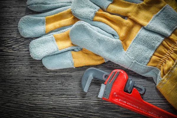 Plumbing pipe wrench safety gloves on wooden board — Stock Photo, Image