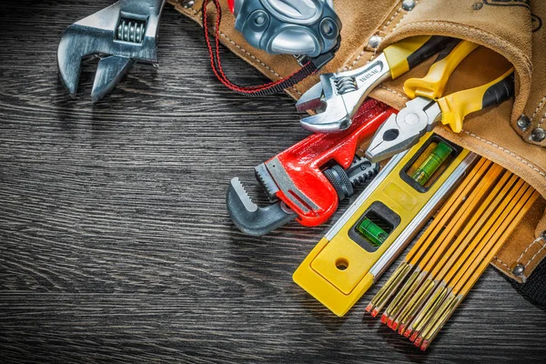 Leather tool belt with construction tooling on wooden board — Stock Photo, Image