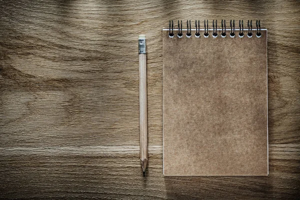 Lápis caderno marrom na placa de madeira — Fotografia de Stock