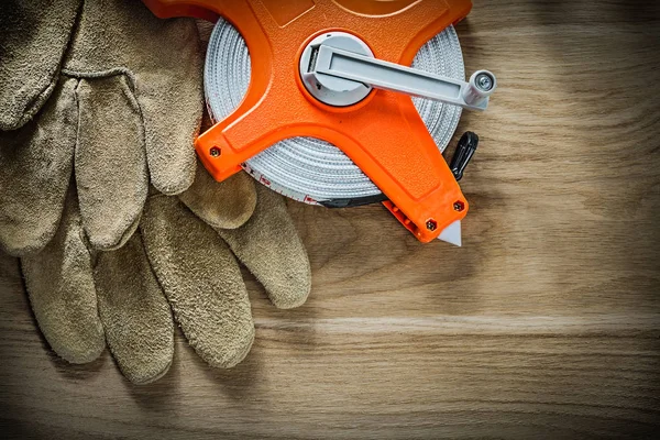 Leather protective gloves tape measure on wooden board — Stock Photo, Image