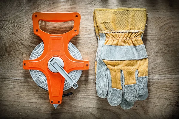 Par de guantes de seguridad cinta métrica en tablero de madera —  Fotos de Stock