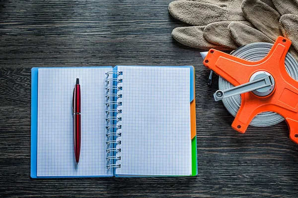 Measuring tape protective gloves notebook pen on wooden board — Stock Photo, Image