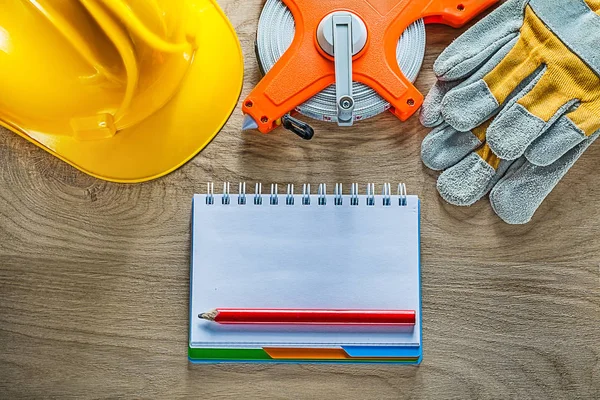 Cuaderno lápiz guantes de seguridad cinta métrica casco del edificio en wo —  Fotos de Stock