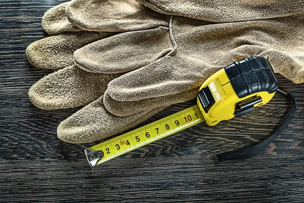 Tapeline leather safety gloves on wooden board — Stock Photo, Image