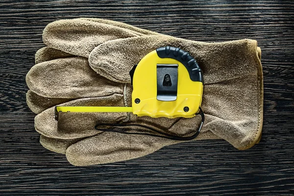 Tapeline leather protective gloves on wooden board — Stock Photo, Image