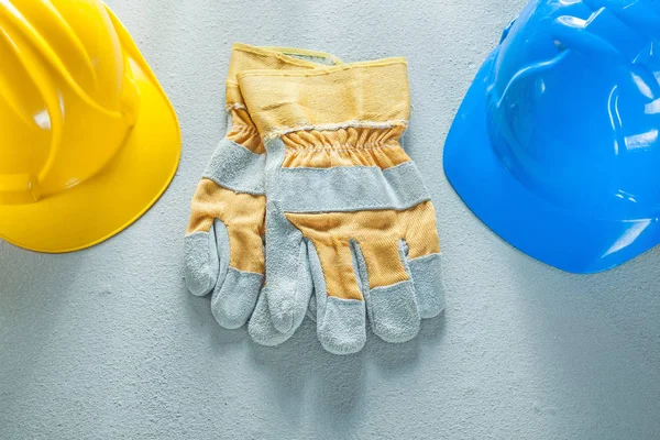 Safety gloves hard hats on concrete background