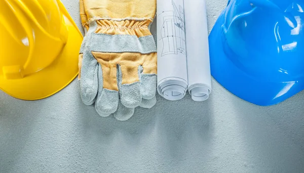 Beschermende handschoenen veiligheidshelmen blauwdrukken op concrete achtergrond — Stockfoto