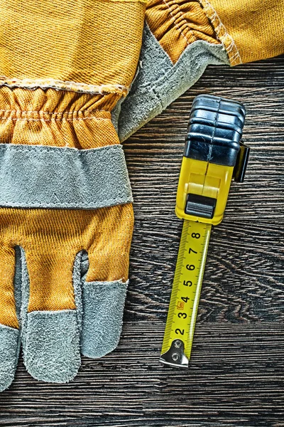 Tape measure safety gloves on wooden board