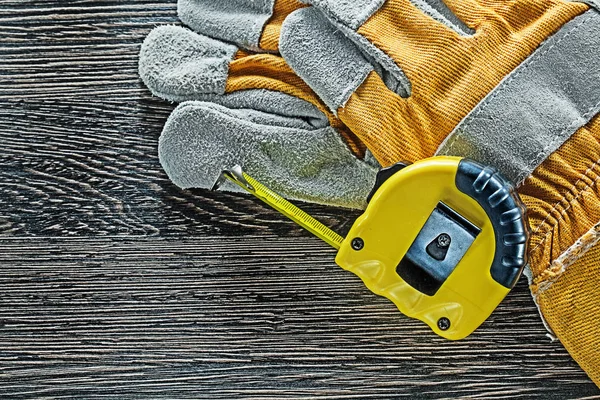 Tape measure pair of protective gloves on wooden board — Stock Photo, Image